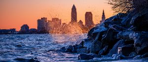 Preview wallpaper water, waves, spray, stones, city, sunset