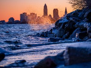 Preview wallpaper water, waves, spray, stones, city, sunset