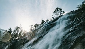 Preview wallpaper waterfall, cliff, trees, sunlight, flare