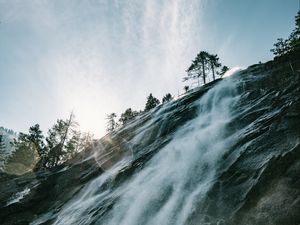 Preview wallpaper waterfall, cliff, trees, sunlight, flare