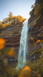 Preview wallpaper waterfall, rock, cliff, grass, flowers, nature