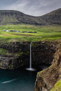 Preview wallpaper waterfall, rock, sea, valley, houses