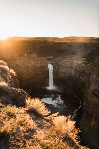 Preview wallpaper waterfall, rocks, cliff, rays, sky
