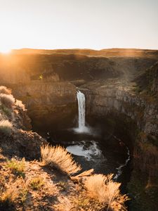 Preview wallpaper waterfall, rocks, cliff, rays, sky
