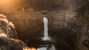 Preview wallpaper waterfall, rocks, cliff, rays, sky