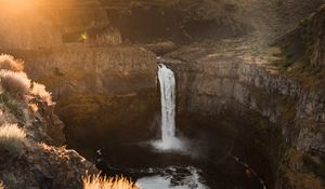 Preview wallpaper waterfall, rocks, cliff, rays, sky