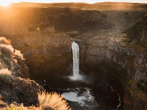 Preview wallpaper waterfall, rocks, cliff, rays, sky