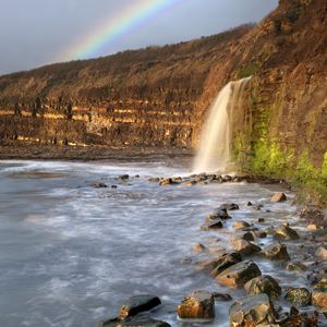 Preview wallpaper waterfall, stones, sea, cliffs, rainbow, nature