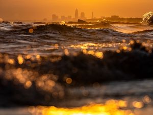 Preview wallpaper waves, sunset, city, buildings, silhouettes