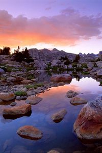 Preview wallpaper wind river range, wyoming, stones, river, mountains, evening, sky, grass