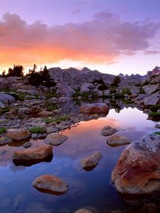 Preview wallpaper wind river range, wyoming, stones, river, mountains, evening, sky, grass